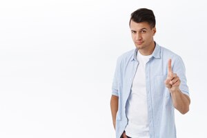 Not so fast portrait of stylish macho man handsome guy shaking index finger in prohibition forbid action smiling confident disagree or scold someone making wrong choice white background