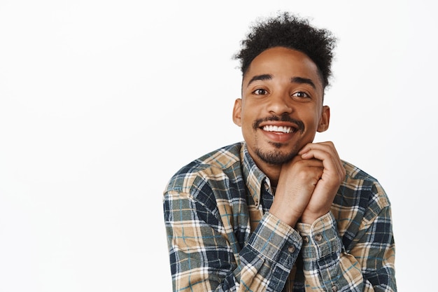 So moving. Close up of cute african american guy with moustache, contemplate smth beautiful, smiling with love and romantic gaze, admire beauty, white background