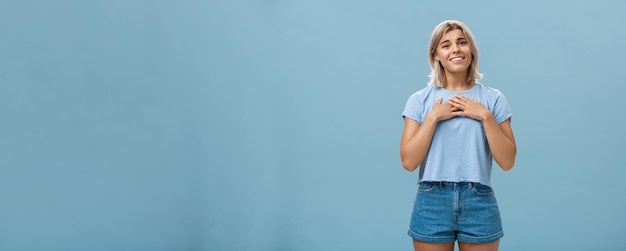 とても甘い感謝は、Tシャツと日焼けした肌のホールディを持つショートパンツの美しく感情的なブロンドの女の子に触れました