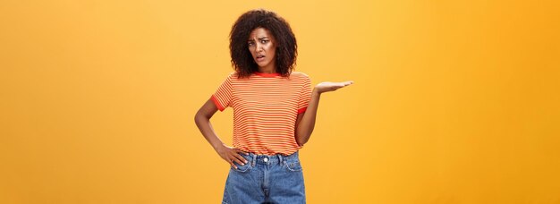 Free photo so what moody unimpressed stylish darkskinned girlfriend with curly hairstyle holding hand on waist