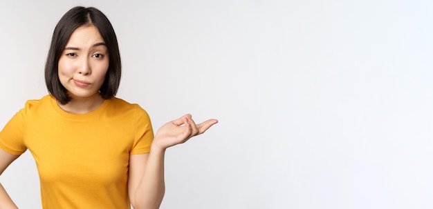 So what unbothered asian woman shrugging looking clueless standing against white background