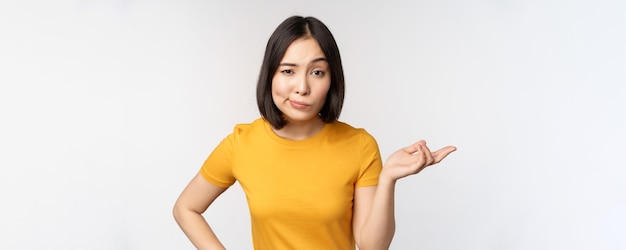 Free photo so what unbothered asian woman shrugging looking clueless standing against white background