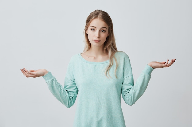 Foto gratuita e allora, a chi importa. incerta dubbiosa donna europea perplessa con i capelli tinti di biondo che scrolla le spalle le spalle in interrogatorio gesto di incertezza e avendo confuso sguardo incapace