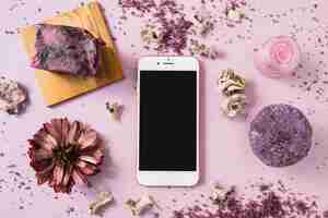 Free photo soap bar; herbal body scrub; dried flower and smartphone on pink background