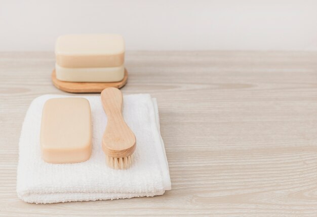 Soap; brush and towel on wooden tabletop