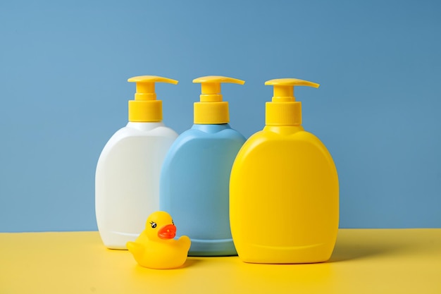 Бутылки мыла или шампуня с милой уткой на синем фоне. детские купальные принадлежности