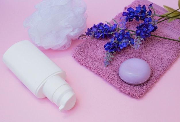 石鹸;タオル;ラベンダー花;湯沸かしポット、ピンクの背景に化粧品のボトル