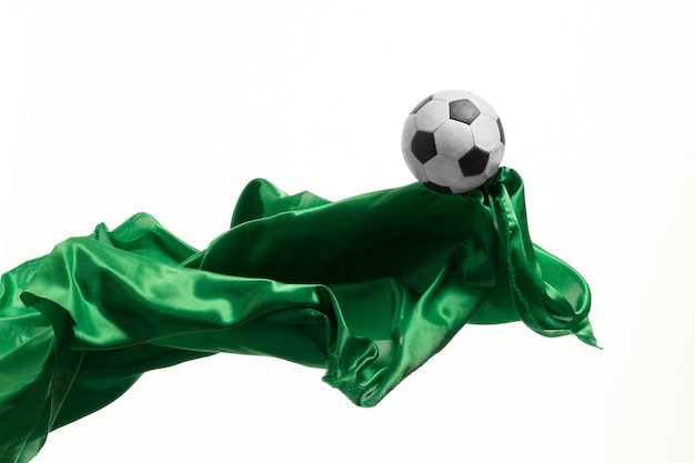 Футбольный мяч и ровная элегантная прозрачная зеленая ткань изолированные или отделенные на белой предпосылке студии.