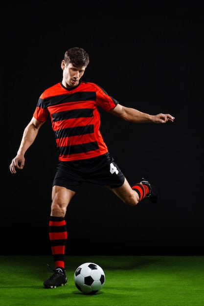 Soccer player kicking ball over black background