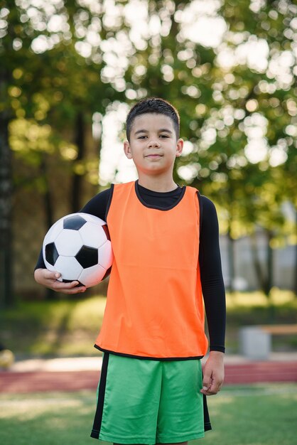 Premium Photo Soccer Player In Orange Vest Holds Ball In One Hand After Training