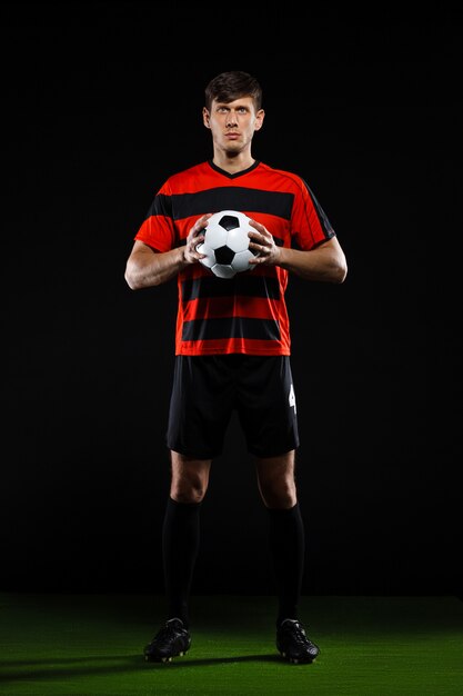 Soccer player staring at green field with ball