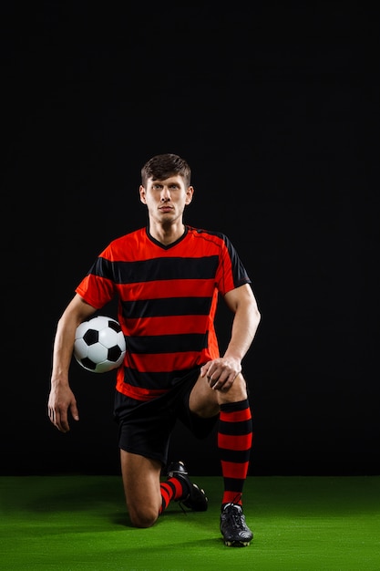 Free photo soccer player with ball standing on knee, play football