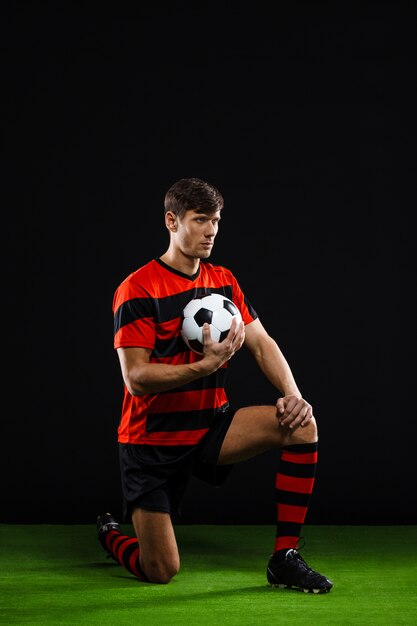 Soccer player with ball standing on knee, play football