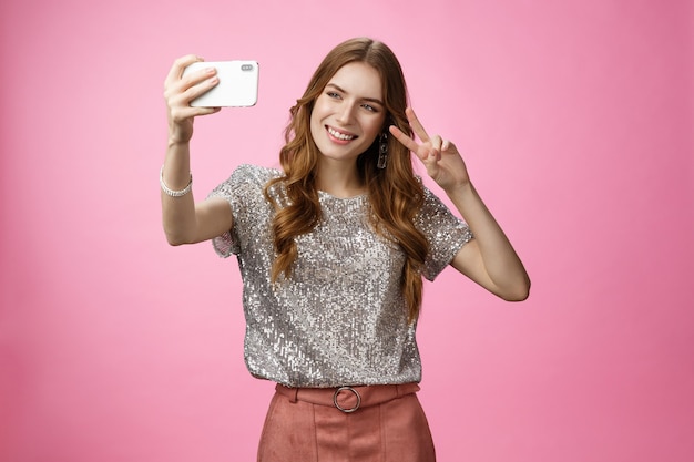 Sociable attractive glamour young caucasian woman taking selfie show victory peace sign smiling broa...