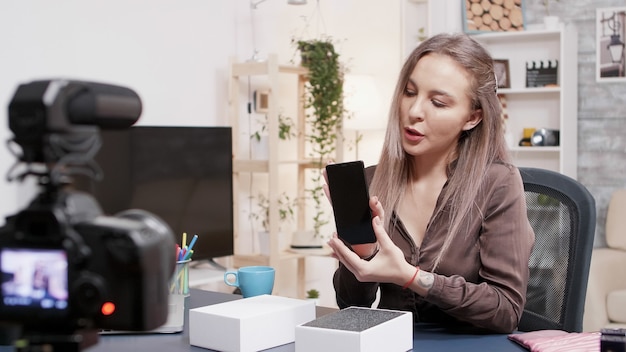 Foto gratuita la star dei social media registra l'unboxing di un nuovo telefono davanti alla telecamera nel suo studio