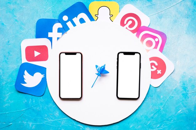 Social mobile application icons around the circular white frame with two cellphone against blue backdrop