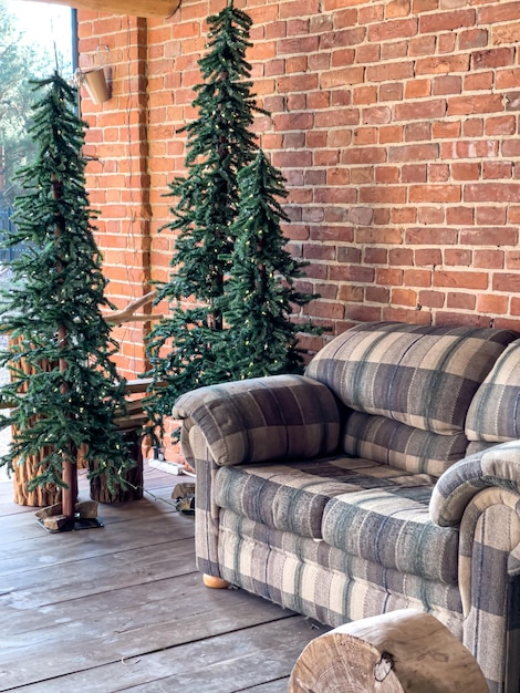 Sofa and christmas trees on the background of a brick wall house exterior