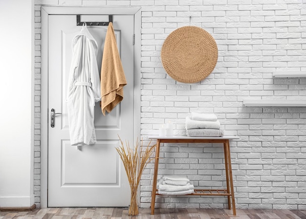 Soft comfortable bathrobe and towel hanging on door in stylish room interior