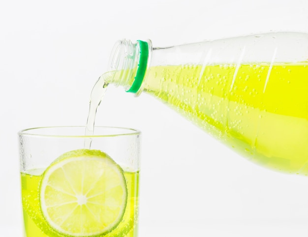 Soft drink being poured into glass with lime