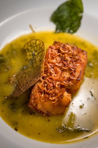 Soft focus of a cod fish dish with a relish of Spinach in a white bowl