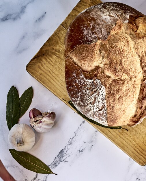 Бесплатное фото Мягкий фокус свежеиспеченного традиционного хлеба на деревянной доске с чесноком