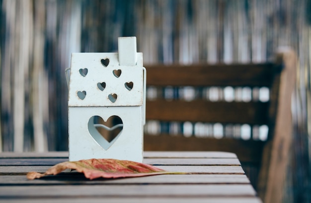 Soft focus shot of a house shaped lantern with heart holes on a wooden table