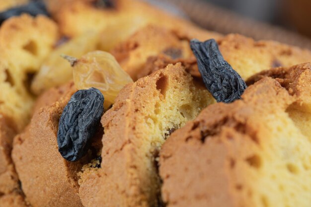 Soft pie slices with black sultana on wooden board.