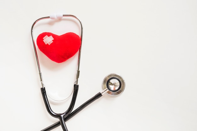 Soft red heart with stethoscope on white background