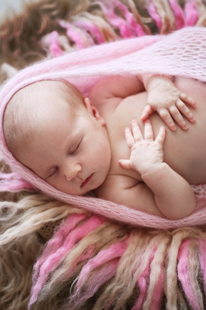 Soft sleeper newborn girl in pink on beige wool