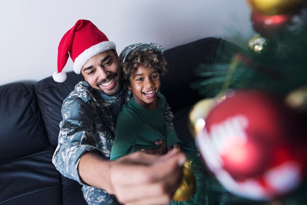 그의 딸과 함께 크리스마스 트리를 장식하는 군인