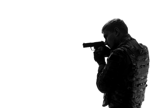 Free photo soldier silhouette tough handsome serious strong army soldier in uniform concentrated with gun