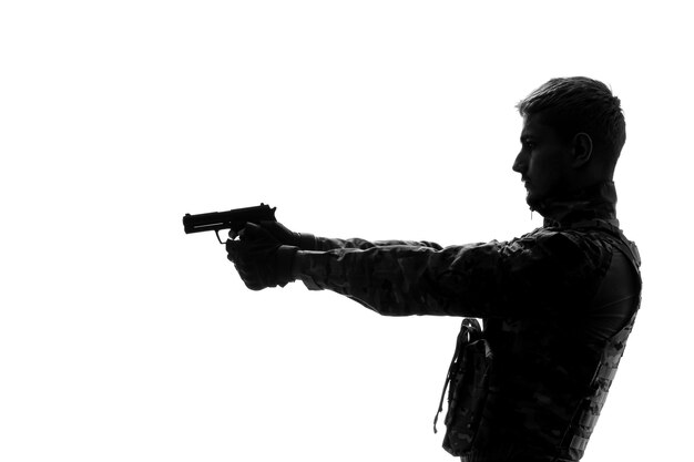 Солдатский силуэт крутой красивый серьезный сильный армейский солдат в форме, указывающий пистолетом