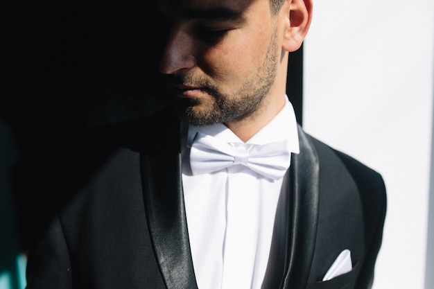 Solid brunette groom in black suit indoor sunlight