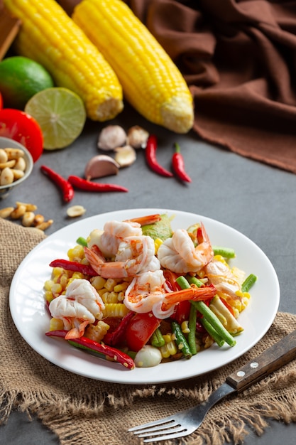 Free photo som tum with corn and shrimp, served with rice noodles and green salad decorated with thai food ingredients.