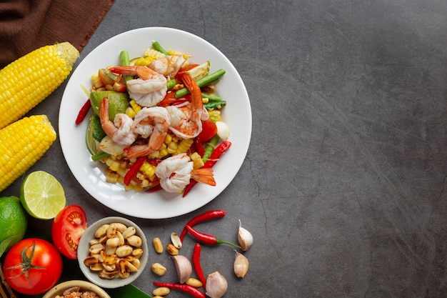 Free photo som tum with corn and shrimp, served with rice noodles and green salad decorated with thai food ingredients.