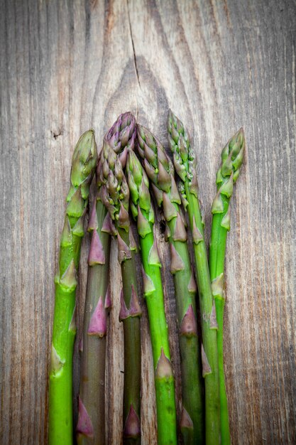 Some asparagus on wooden background, top view. vertical
