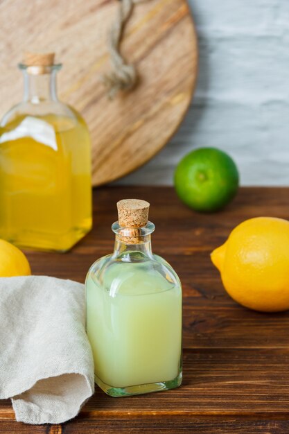 レモンジュースのボトル、木製と白い表面に白い布、高角度のビューとレモンジュースのいくつかのボトル。