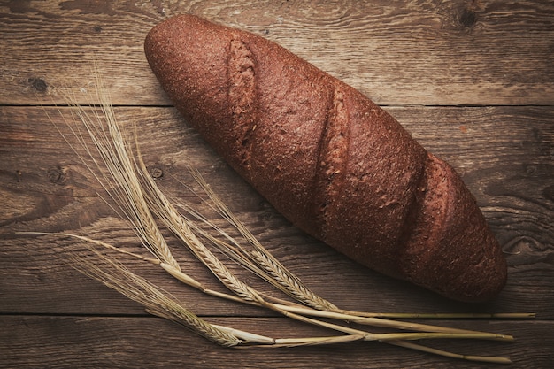 Some bread and wheat on wooden, flat lay.