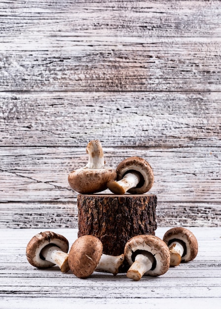 Free photo some of brown mushrooms on a wood stub on light wooden table