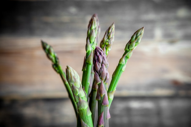 Some a bunch of asparagus on dark wooden background, side view.