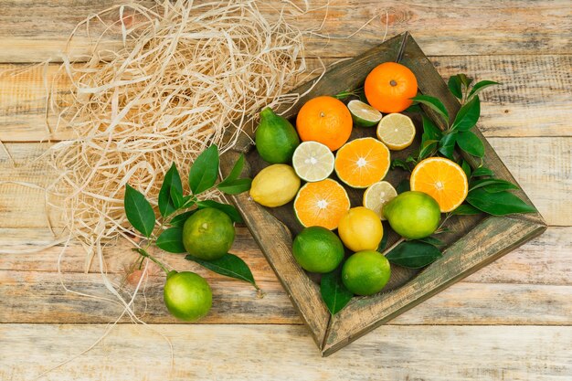 Some citrus fruits in a bronze plate on wooden board