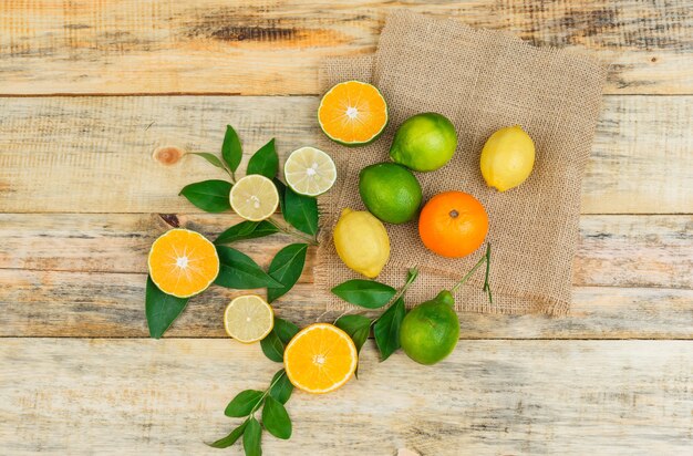 Some citrus fruits with leaves on a linen placemat on wooden board