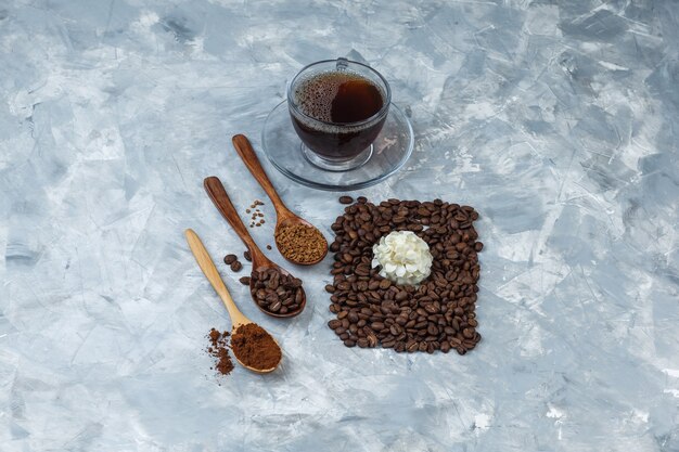 Некоторые кофейные зерна, чашка кофе с кофейными зернами, растворимый кофе, кофейная мука в деревянной ложке
