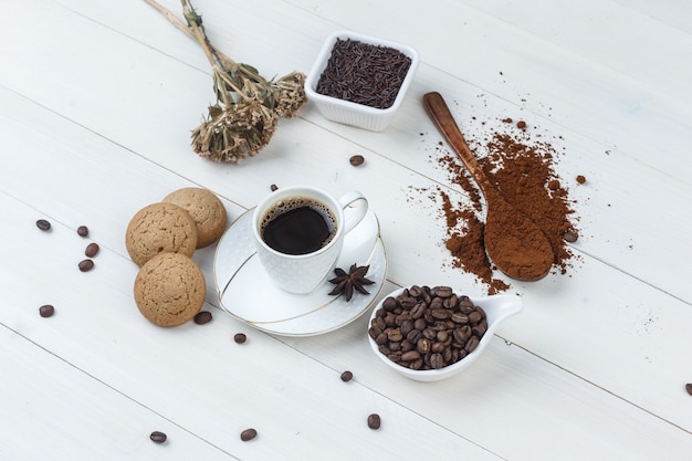 Some coffee with grinded coffee, coffee beans, dried herbs, cookies