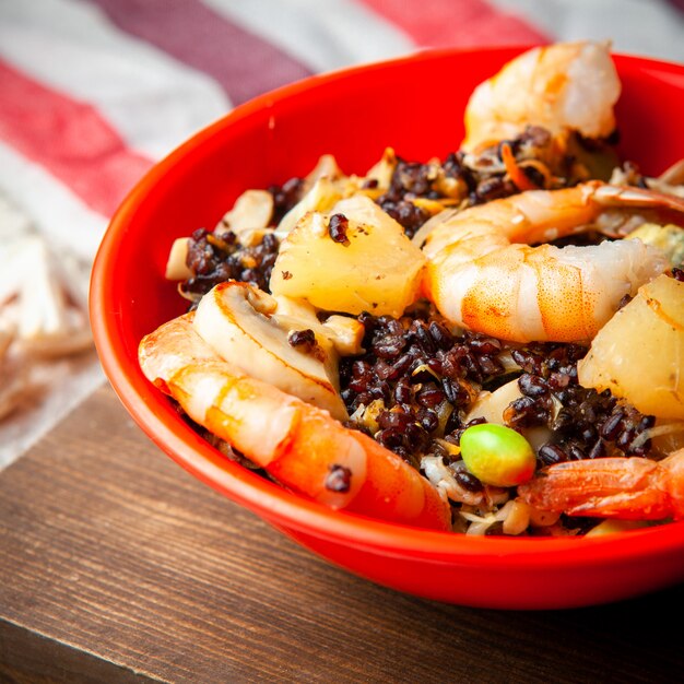 Some delicious meal with crevettes in a red plate on wooden background high angle view.