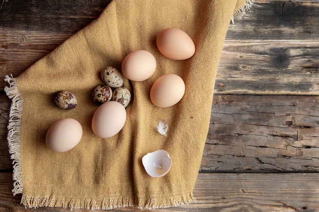 Some eggs with broken one on cloth and dark wooden background, top view.