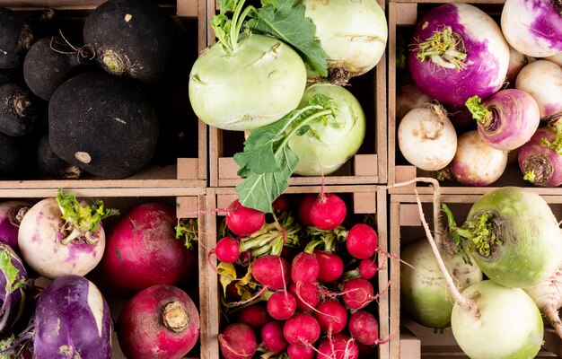 Some of fresh red, black, white and different radishes in a wooden farmer case top view.