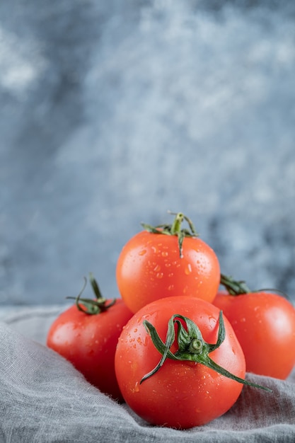 Some of fresh tomatoes on a gray tablecloth . 