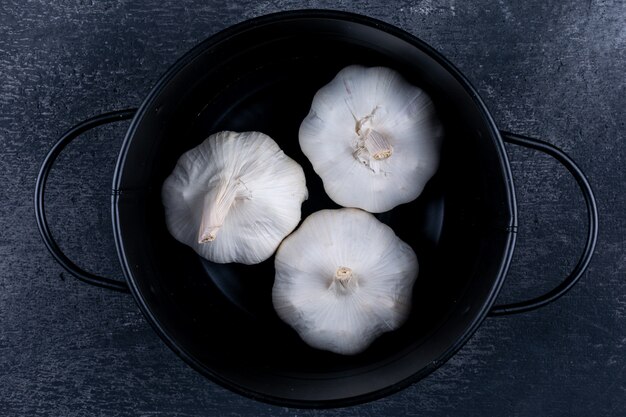 Some garlic in a black pot flat lay