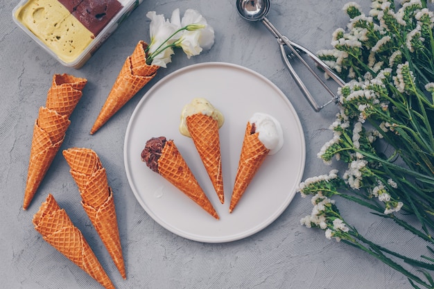 Some ice cream in plate with flowers on white, top view.